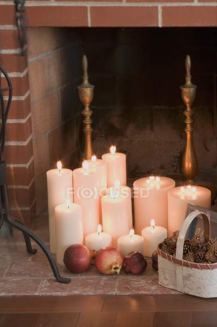 Closeup view of candles, pomegranates and cones in front of fireplace — Stock Photo