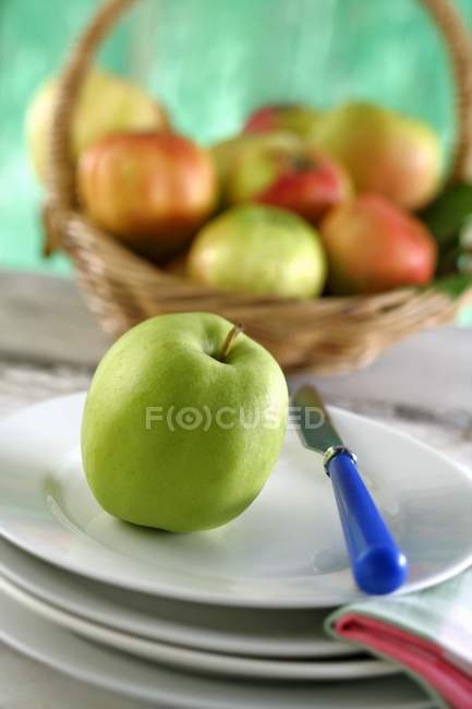Apple on plates with knife — Stock Photo