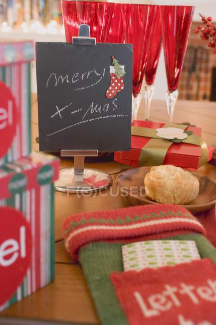 Merry X-mas writing on black board near glasses and place setting on table by fireplace — Stock Photo
