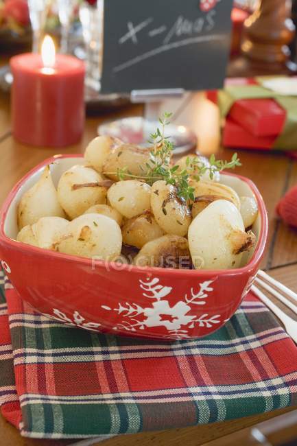 Cebolas vitrificadas em prato vermelho na mesa de Natal com toalha — Fotografia de Stock