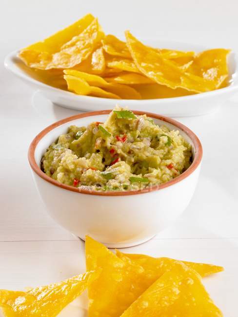 Tigela de Guacamole com Chips na superfície branca — Fotografia de Stock
