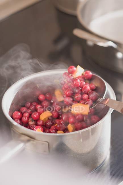 Closeup view of boiling cranberries and oranges in pot — Stock Photo
