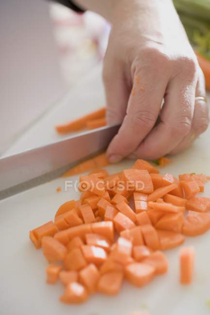 Mão humana cortando cenouras — Fotografia de Stock