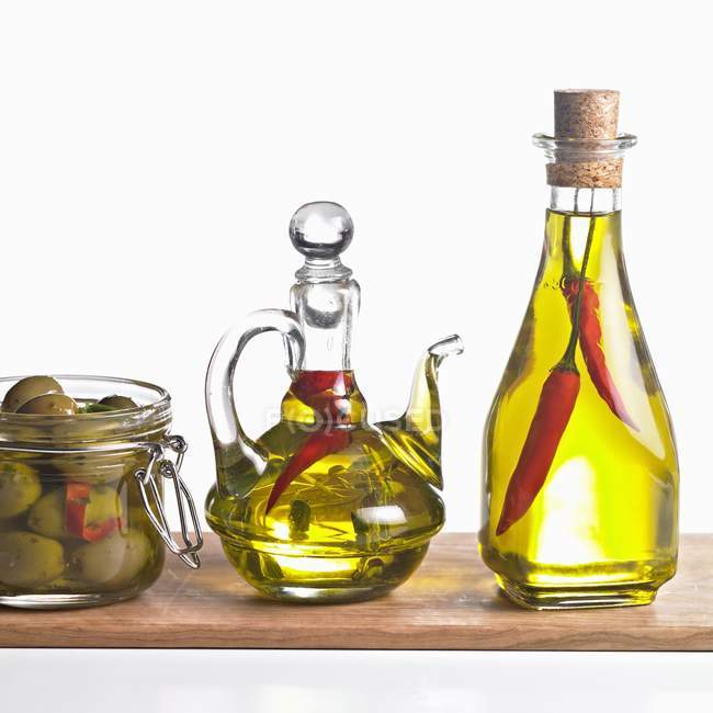 Olives with bottles of chilli oil and herbs — Stock Photo