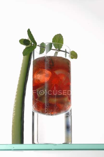 Red beverage with cucumber in glass on white background — Stock Photo