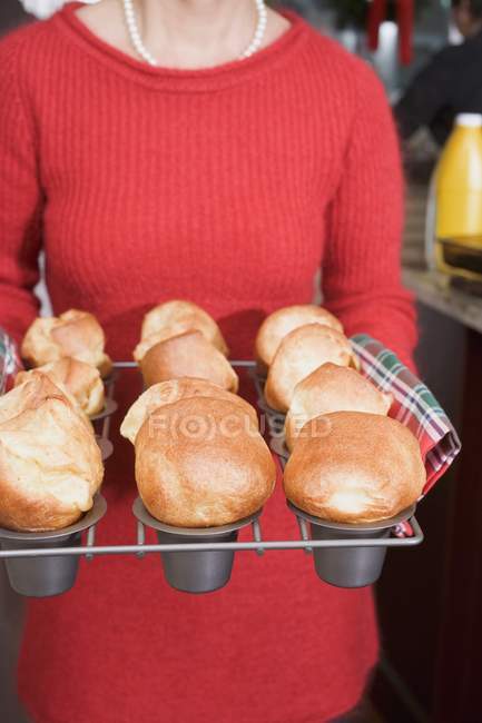 Femme tenant des popovers fraîchement cuits sur un rack — Photo de stock