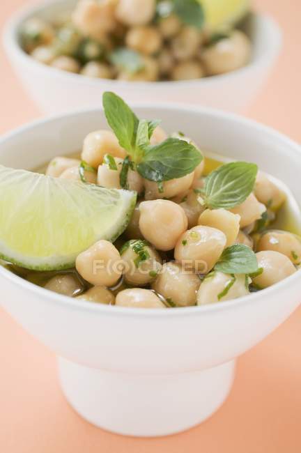 Chick-peas with lime wedges and herbs on white plate — Stock Photo