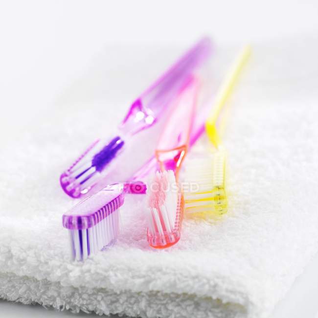 Вид крупным планом красочных зубных щёток на белом полотенце — стоковое фото