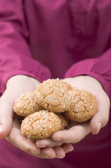 Cropped view of hands holding Amaretti cookies with sugar — Stock Photo