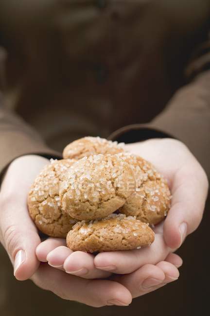 Крупный план обрезанных рук, держащих печенье Амаретти — стоковое фото