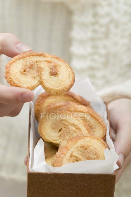 Hand taking puff pastry biscuit — Stock Photo