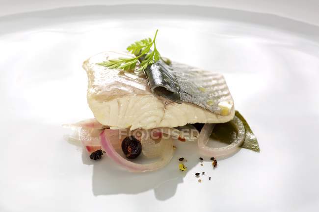 Trout fillet poached in wine with onion on white surface — Stock Photo