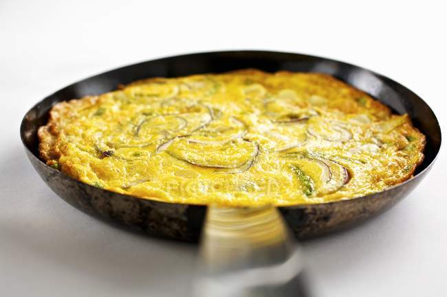 Frittata with onions and asparagus in pan  on white background — Stock Photo