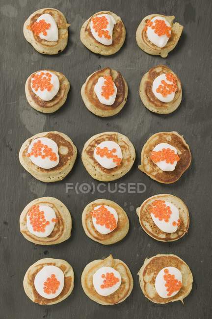 Fritters with sour cream and caviar — Stock Photo