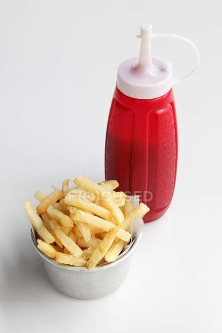 Potato fries and bottle of ketchup — Stock Photo