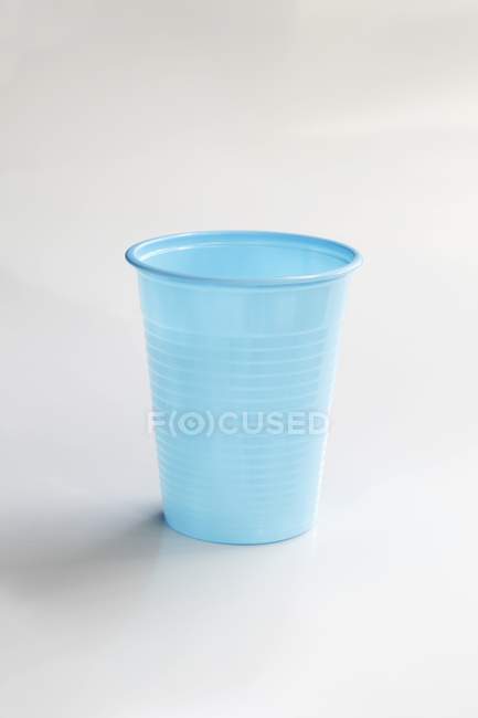 Vista de primer plano de una taza de plástico azul en la superficie blanca - foto de stock