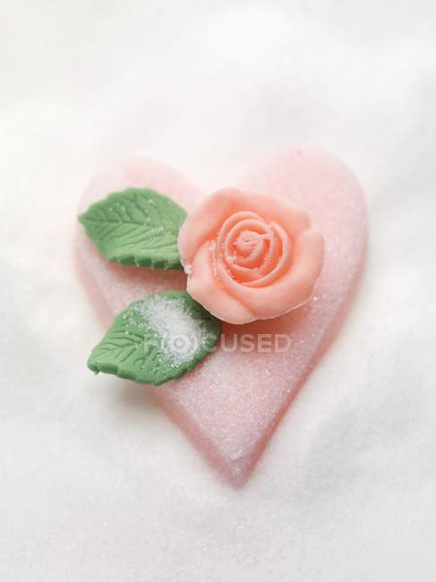 Vista de primer plano del corazón de azúcar rosa con rosa de mazapán - foto de stock