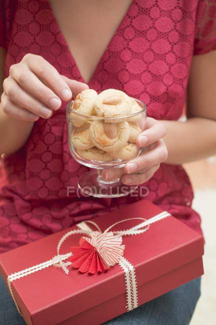Vista recortada de la mujer que busca galletas de almendras en vidrio - foto de stock