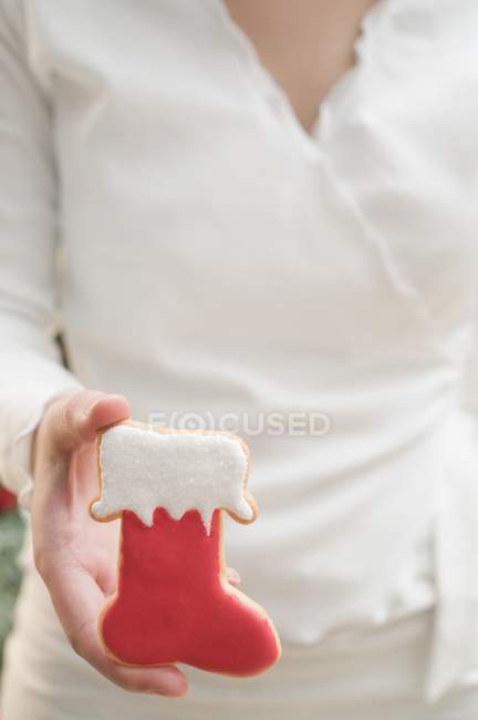 Vista recortada de la mujer sosteniendo galleta de Navidad en forma de bota roja - foto de stock