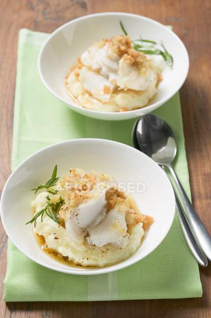Schellfisch mit Kartoffelkruste auf Kartoffelpüree auf weißen Tellern über grünem Handtuch mit Löffel — Stockfoto