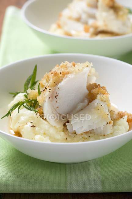 Eglefino con crosta di patate sul purè di patate in piatto bianco — Foto stock