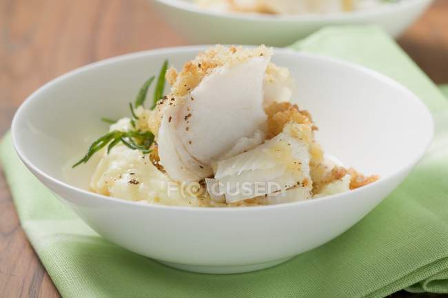 Eglefino con crosta di patate sul purè di patate sul piatto bianco sopra asciugamano verde — Foto stock