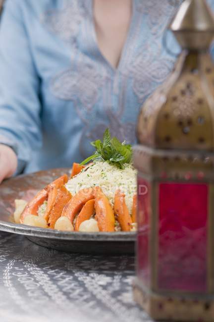 Woman serving couscous with pumpkin — Stock Photo