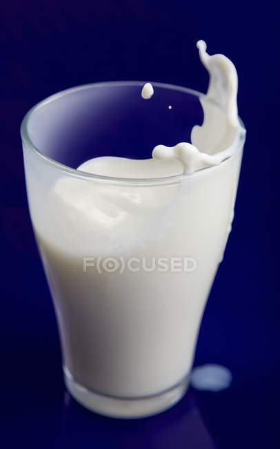 Milch spritzt aus Glas — Stockfoto