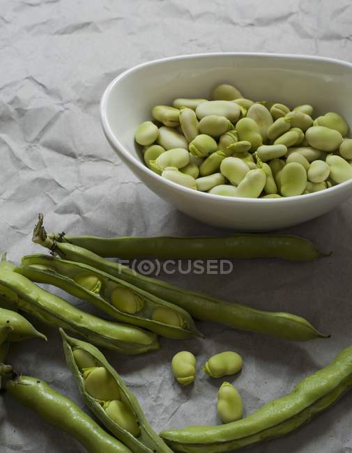 Geschälte Fava-Bohnen in Schale mit Schoten — Stockfoto