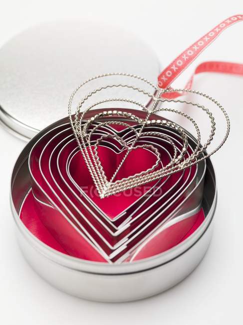 Vista close-up de cortadores de biscoito em forma de coração e cabide com fita — Fotografia de Stock