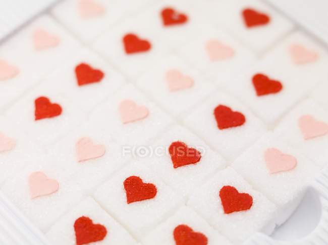 Primo piano vista di cubetti di zucchero con cuori rossi e rosa — Foto stock