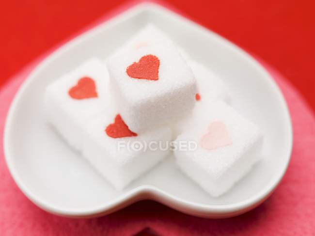 Vue rapprochée des cubes de sucre avec des cœurs rouges — Photo de stock