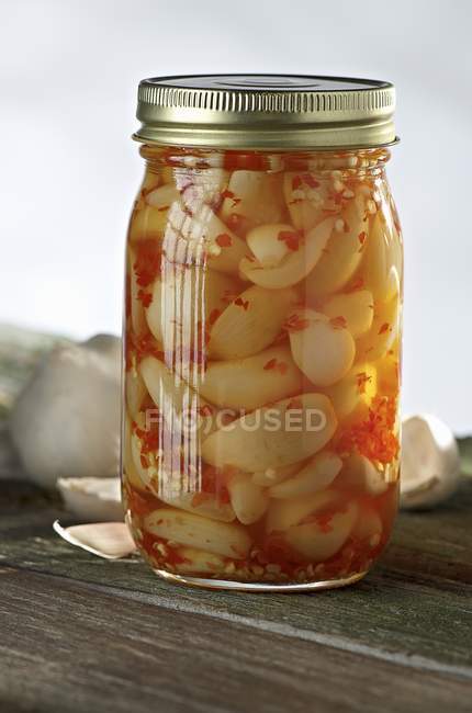 Pickled Hot Pepper Garlic in a Glass Jar over wooden surface — Stock Photo