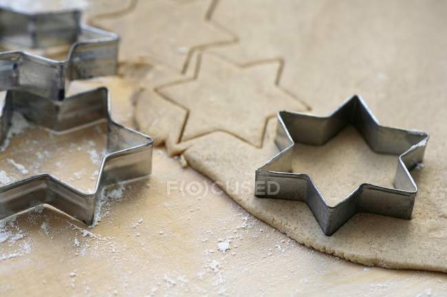 Vista de cerca de la masa de galletas con cortadores en forma de estrella - foto de stock