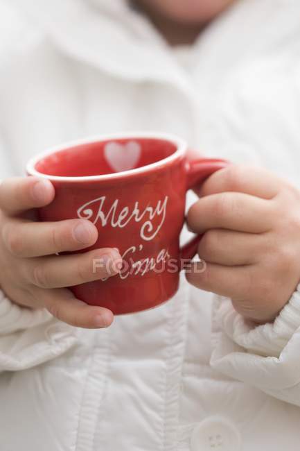Vue rapprochée de l'enfant tenant la tasse de Noël rouge — Photo de stock