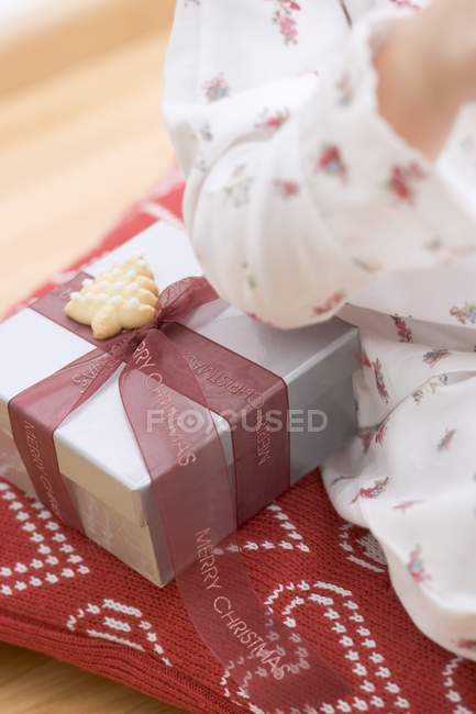 Niño sentado junto a regalo de Navidad - foto de stock