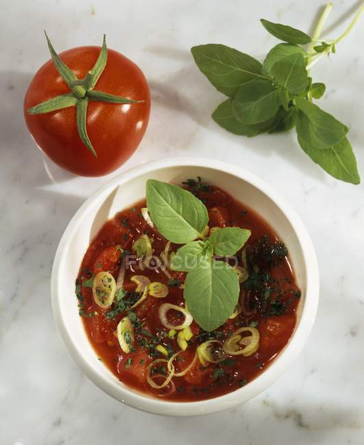 Salsa de tomate con albahaca en tazón blanco - foto de stock