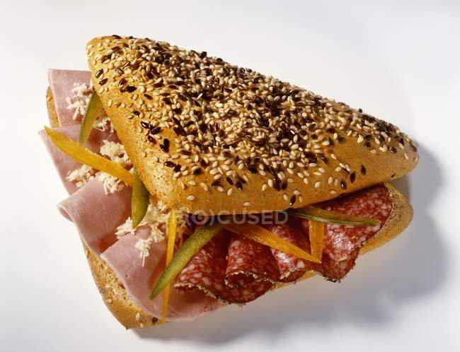 Sesame roll filled with ham and salami — Stock Photo