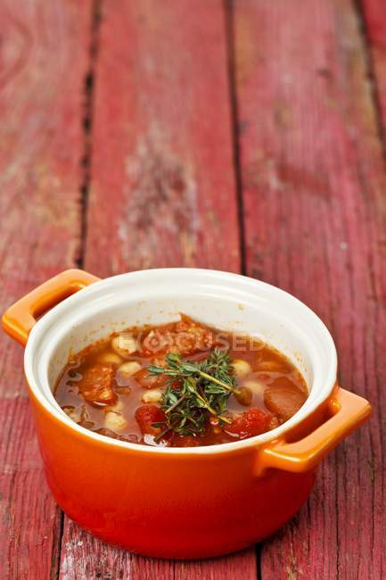 Vegetable stew with chickpeas and sausage in pan over wooden surface — Stock Photo
