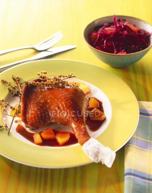 Jambe d'oie avec morceaux de poire et chou rouge sur plaque jaune sur la table — Photo de stock