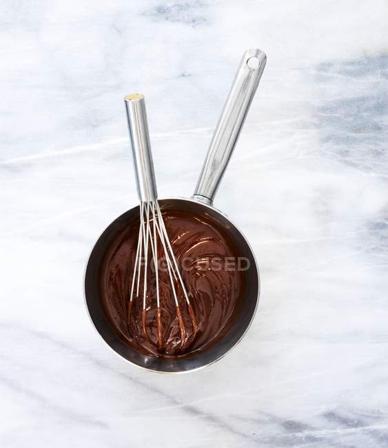 Melted chocolate in saucepan with whisk — Stock Photo