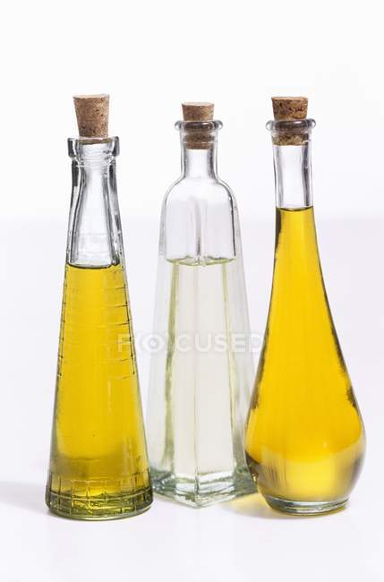 Vista close-up de três óleos diferentes em garrafas sobre fundo branco — Fotografia de Stock