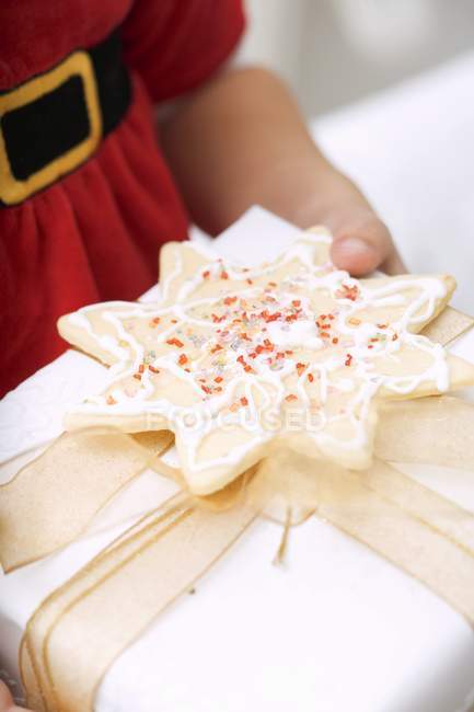 Primer plano vista recortada de niño sosteniendo regalo de Navidad con estrella pastelera - foto de stock