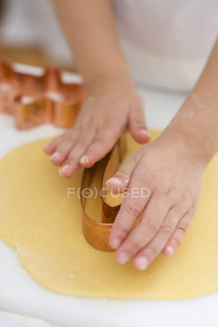 Closeup view of child cutting out a biscuit — Stock Photo