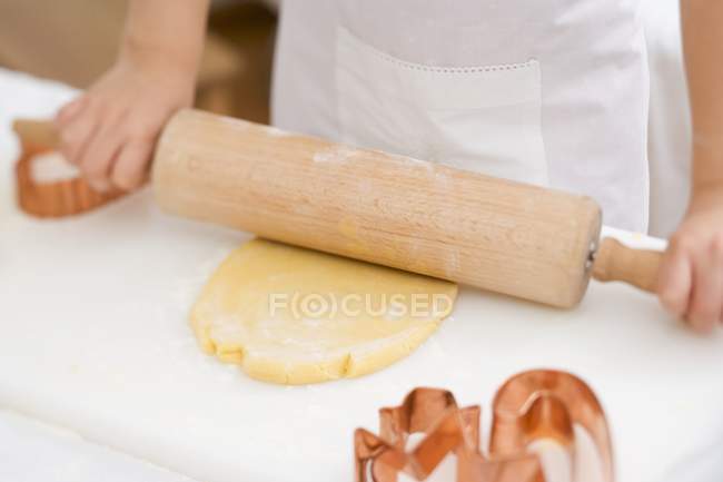 Vue recadrée de l'enfant déroulant la pâte — Photo de stock