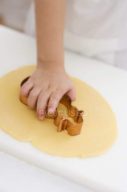 Closeup view of child cutting out biscuit — Stock Photo