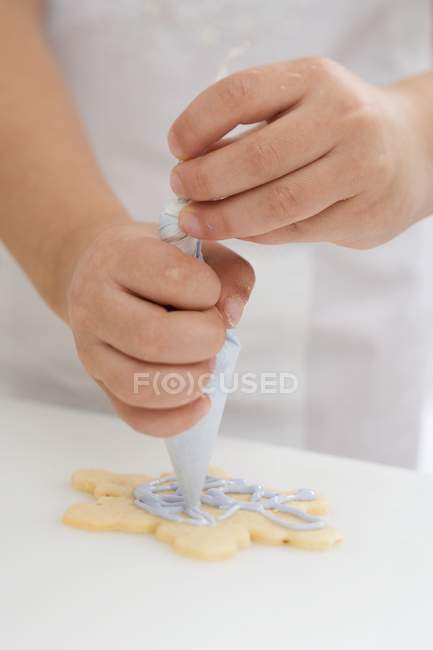 Child decorating sweet Christmas biscuit — Stock Photo