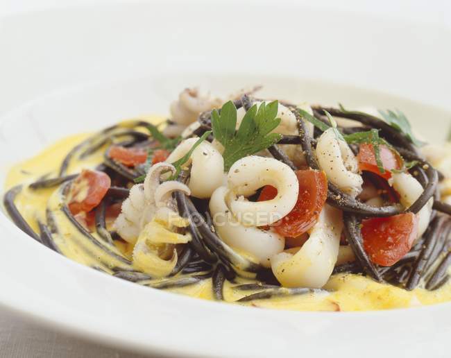 Черные спагетти с мясом кальмаров и помидорами — стоковое фото