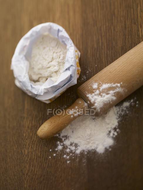 Flour in paper bag and rolling pin — Stock Photo