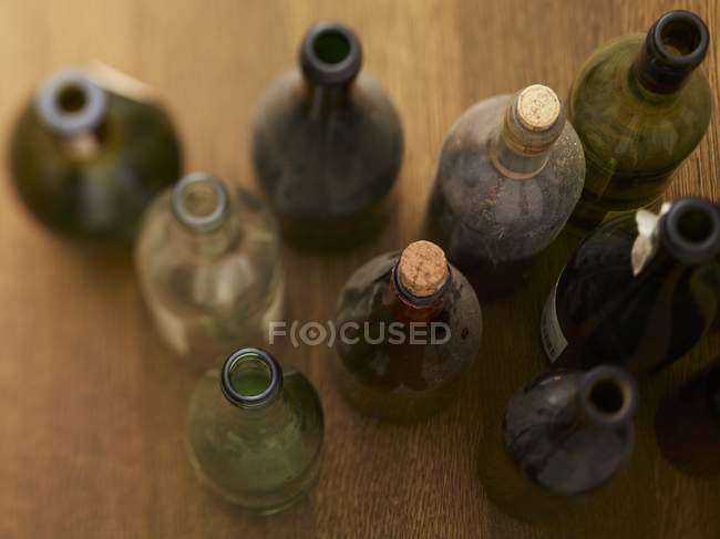 Vista elevada de garrafas de vinho empoeiradas na superfície de madeira — Fotografia de Stock